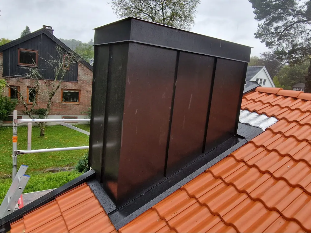 Mørkt pipebeslag med ren avslutning mot tekkingen